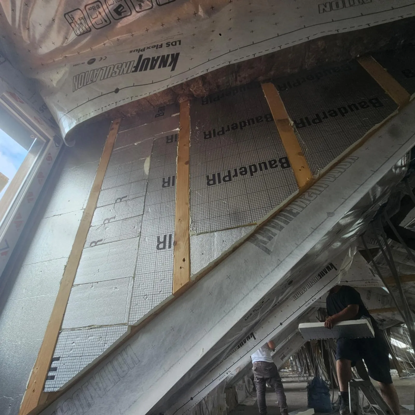 Dachgeschossausbau: PIR-Dämmplatten zwischen den Sparren, Handwerker bei der Arbeit